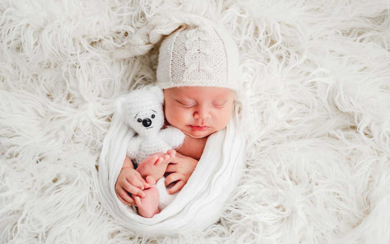 A darling newborn baby snuggles with a teddy bear