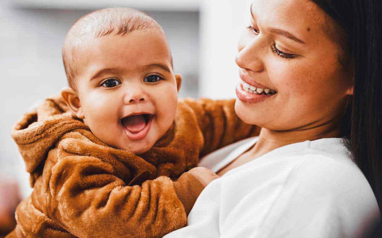 A happy baby held by a joyful newborn care specialist
