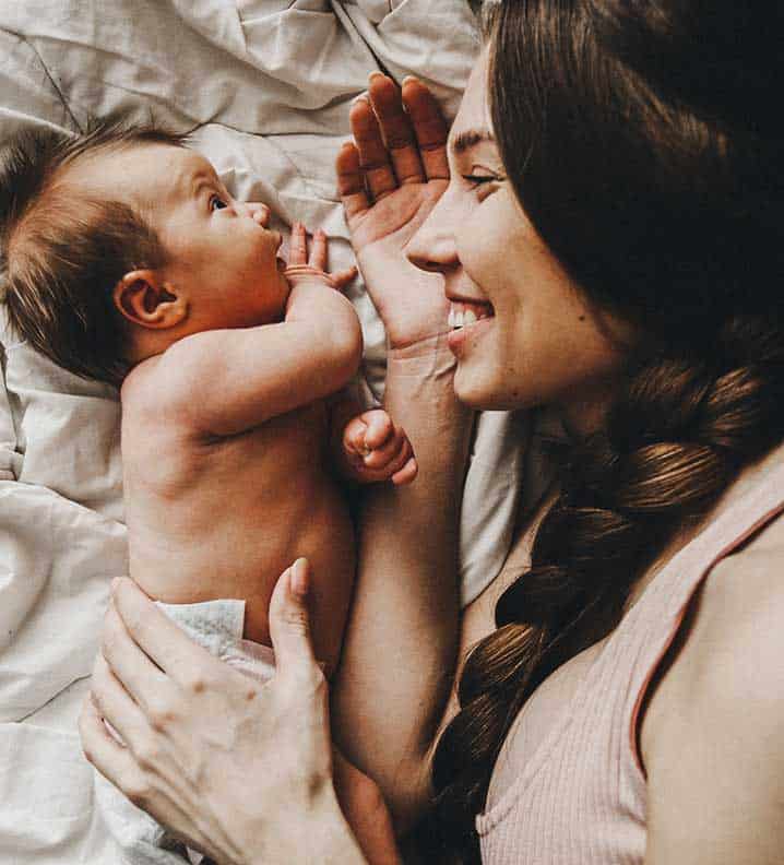 Household Staffing Newborn Care - A woman smiles while bonding with a newborn baby